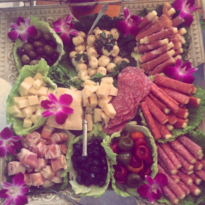 An antipasto spread of meats, cheeses and vegetables with purple flowers