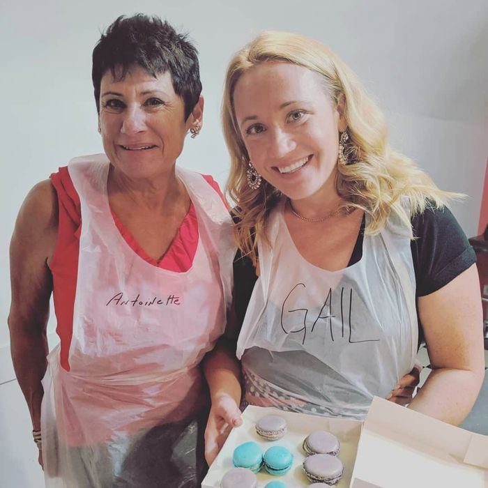 Chef Antoinette in an apron at a French macaron class, holding a box of macarons