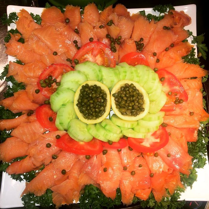 A smoked salmon platter arranged in a decorative pattern with capers